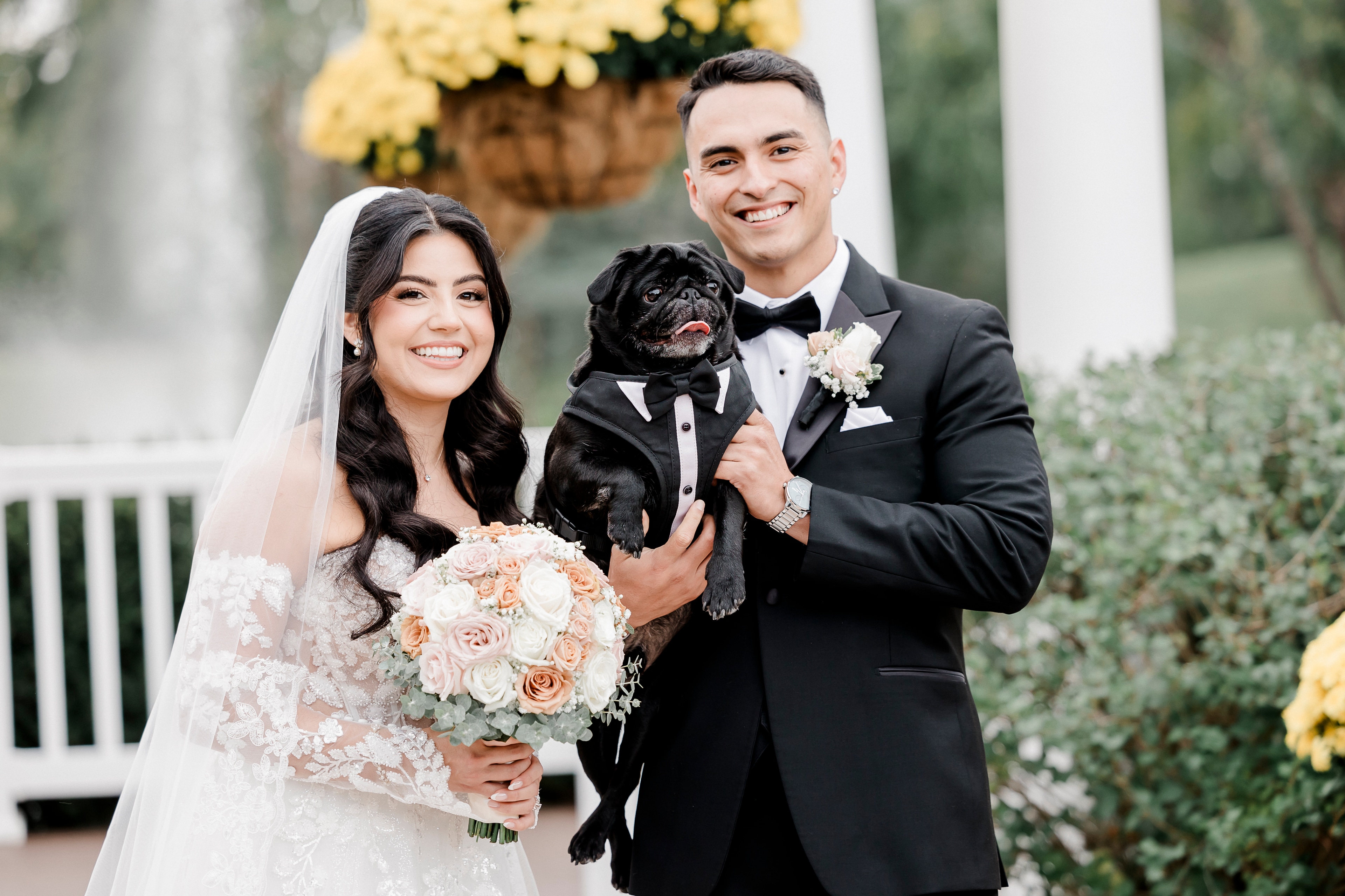 A bride and groom holding their dog on their wedding day
