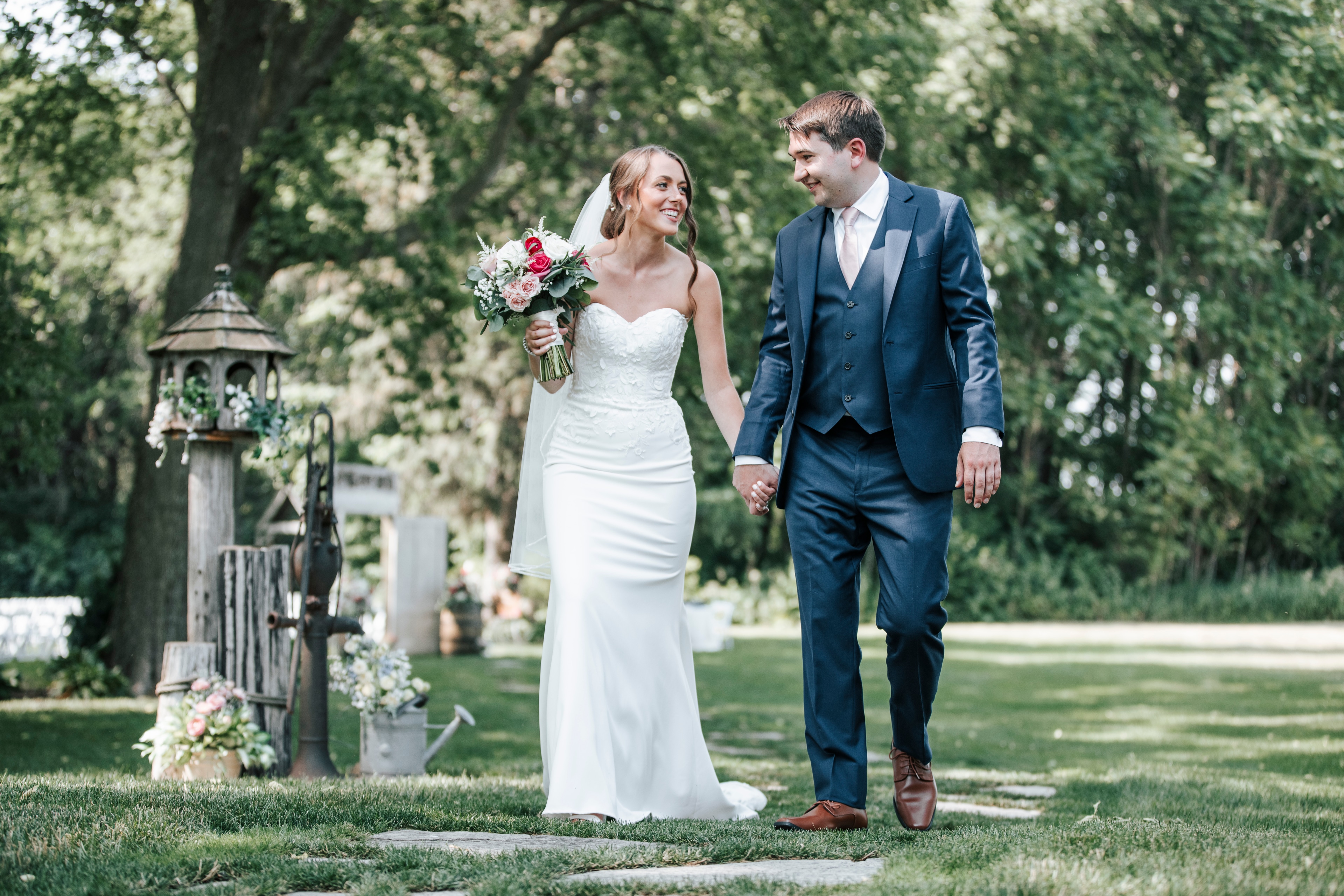 A bride and groom walking hand in hand through a garden